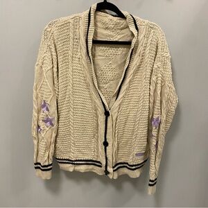 Woman’s beige cardigan with purple stars on sleeves